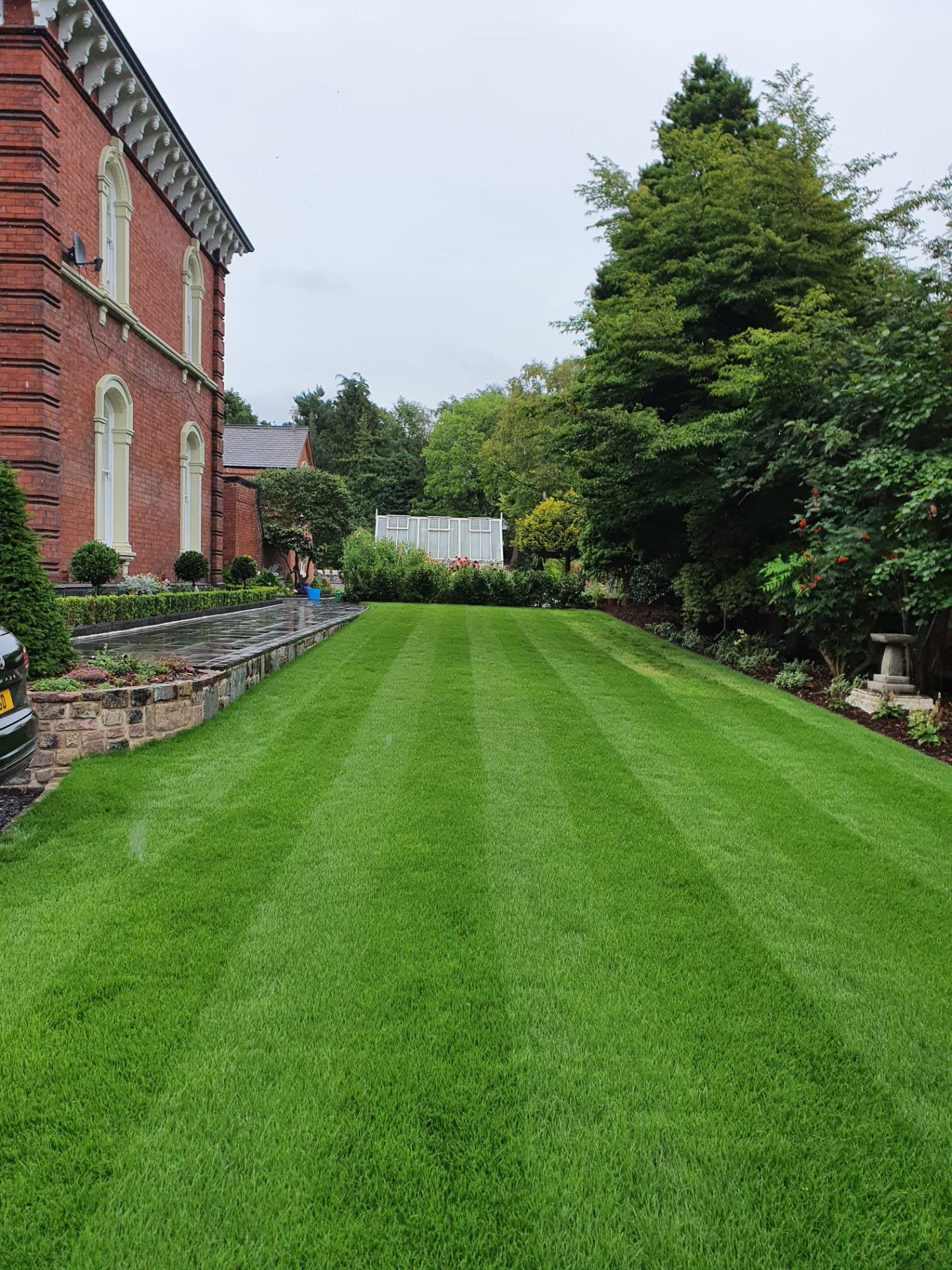 Striped manicured lawn beside a Victorian red-brick house
